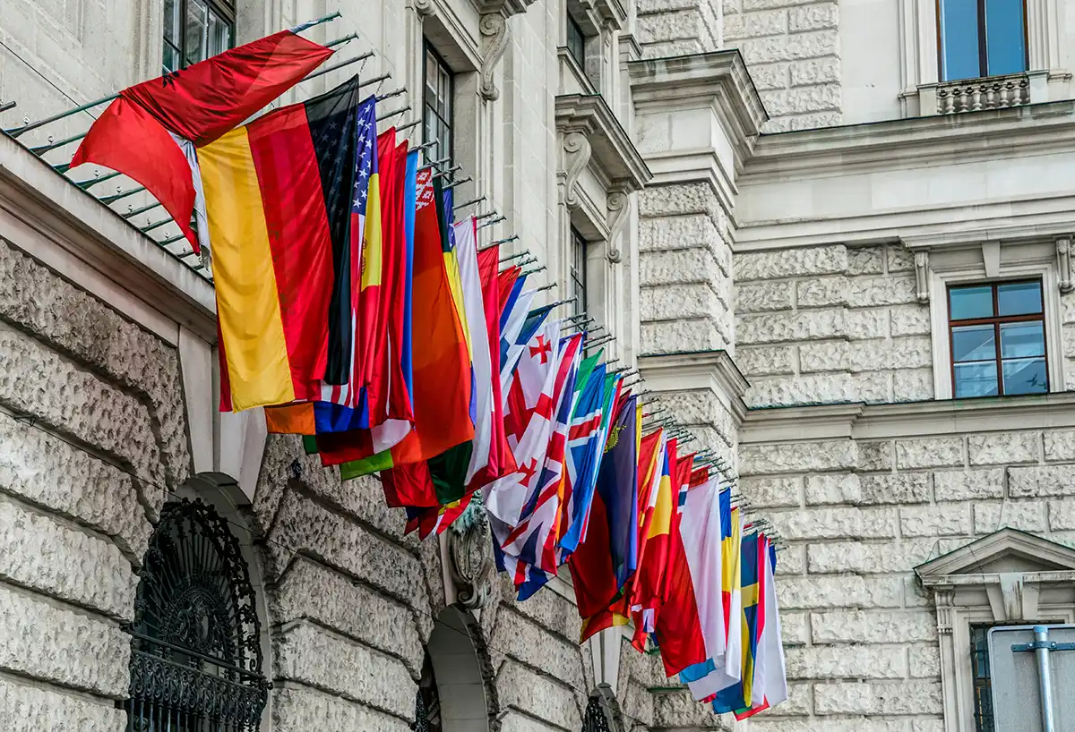 Hilera de banderas nacionales en la fachada de un edificio diplomático, símbolo de las representaciones internacionales que mantiene un ministerio de Asuntos Exteriores en todo el mundo.