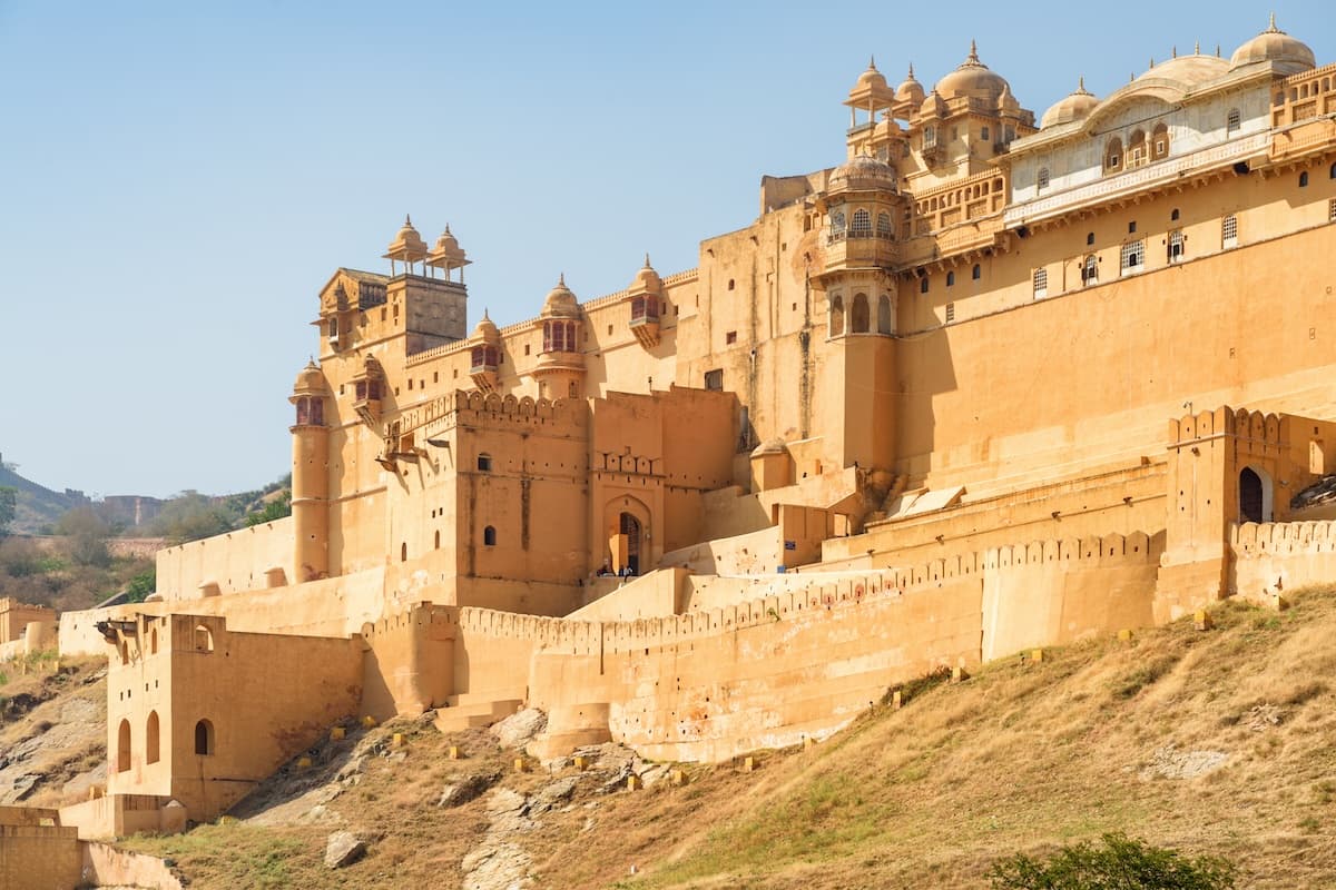 El Fuerte de Amber sobre el lago Maota cerca de Jaipur en Rajastán — muros de arenisca, patios escalonados y las colinas Aravalli.